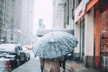 Rear View Of Man Walking On City Street In Schnee - EYF04957