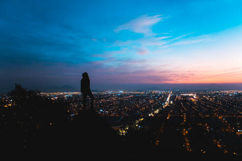 Silhouette Mann bei beleuchteter Stadt gegen Himmel bei Nacht - EYF04983