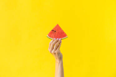 Cropped Hand der Frau hält Wassermelone gegen gelben Hintergrund - EYF04998