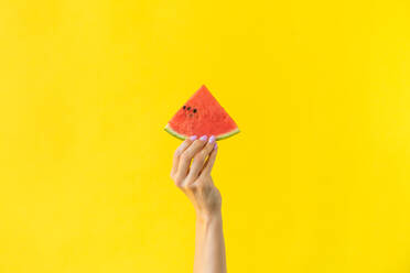 Cropped Hand Of Woman Holding Watermelon Against Yellow Background - EYF04998