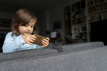 Porträt eines Mädchens im Kleinkindalter, das zu Hause sein Smartphone benutzt - VABF02797