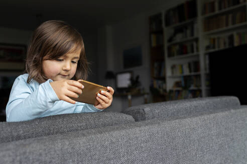 Portrait of toddler girl using smartphone at home - VABF02797