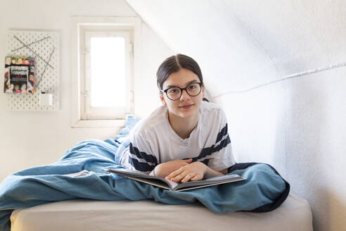 Porträt eines auf dem Bett liegenden Mädchens mit Schulheft - LVF08818