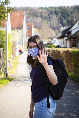Teenager-Mädchen auf dem Weg zur Schule, mit Gesichtsmaske, lizenzfreies Stockfoto