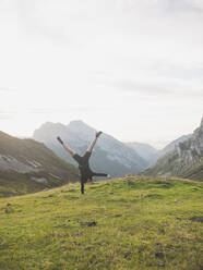 Spain, Cantabria, Young woman performing handstand in Picos de Europa - FVSF00143