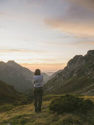 Spanien, Kantabrien, Junge Frau bewundert Tal in Picos de Europa bei stimmungsvoller Morgendämmerung - FVSF00147