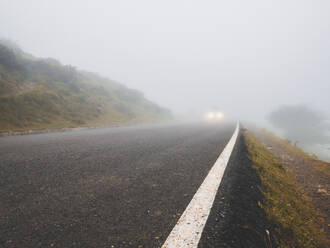 Spanien, Kantabrien, Dichter Nebel umhüllt Asphaltstraße in Picos de Europa - FVSF00161