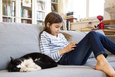 Mädchen sitzt auf der Couch und benutzt ein digitales Tablet - LVF08822