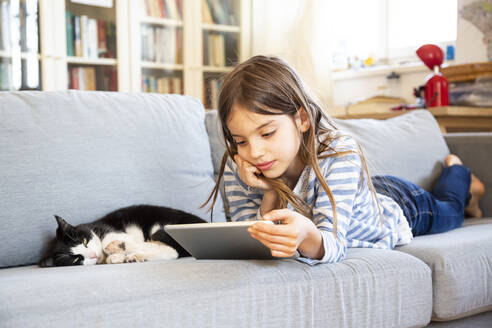 Porträt eines Mädchens, das auf der Couch liegt und ein digitales Tablet benutzt - LVF08824