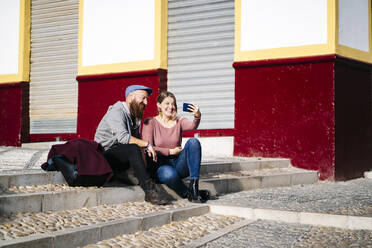 Ein glückliches Paar macht ein Selfie in der Stadt - DGOF00809