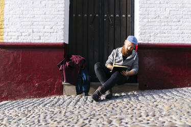 Mann sitzt auf einer Treppe in der Stadt und zeichnet eine Skizze, Granada, Spanien - DGOF00815