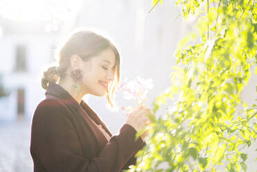 Smiling woman with a blossom in a scenic alley in the city - DGOF00829