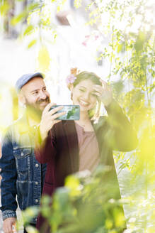 Glückliches Paar macht ein Selfie in einer malerischen Gasse in der Stadt - DGOF00832