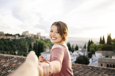 Porträt einer glücklichen Frau, die sich an den Händen hält, mit Alhambra im Hintergrund, Granada, Spanien - DGOF00841