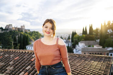 Porträt einer lächelnden Frau mit der Alhambra im Hintergrund, Granada, Spanien - DGOF00845