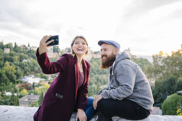 Glückliches Paar macht ein Selfie mit der Alhambra im Hintergrund, Granada, Spanien - DGOF00847