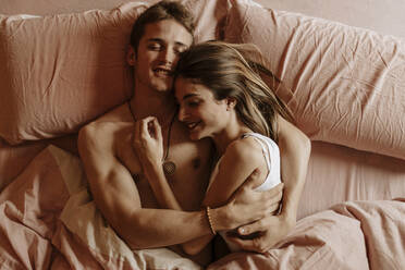 Glückliches junges Paar im Bett liegend - GMLF00034