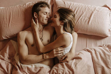 Glückliches junges Paar im Bett liegend - GMLF00035