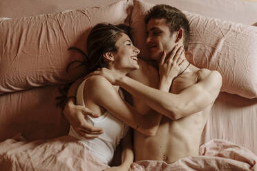 Happy young couple lying in bed - GMLF00037