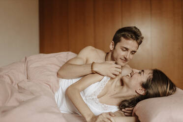 Glückliches junges Paar im Bett liegend - GMLF00043