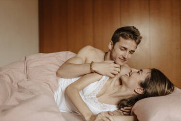 Happy young couple lying in bed - GMLF00043