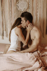 Intimate young couple hugging and kissing in bed - GMLF00044