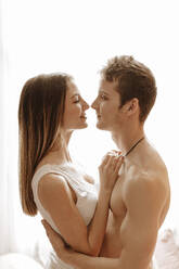 Intimes junges Paar, das sich im Schlafzimmer umarmt - GMLF00052