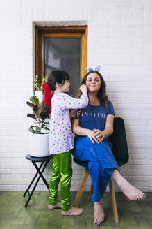 Tochter malt farbenfrohes Make-up auf das Gesicht der Mutter - ERRF03458