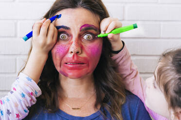 Töchter malen farbenfrohes Make-up auf das Gesicht der Mutter - ERRF03461
