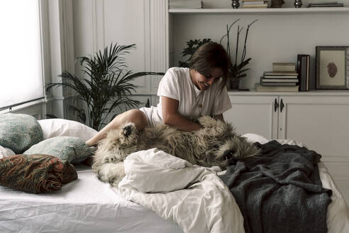 Mature woman cuddling her dog on bed - ERRF03475