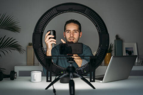 Youtuber talking about photography while filming with smartpone at home stock photo