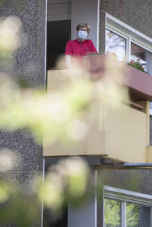 Senior woman wearing mask on balcony, retirement home - JATF01184