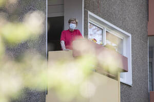 Senior woman wearing mask on balcony, retirement home - JATF01185