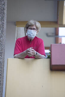 Senior woman wearing mask on balcony, retirement home - JATF01186