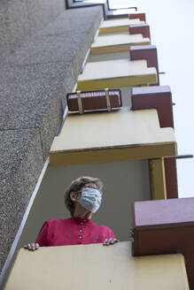 Senior woman wearing mask on balcony, retirement home - JATF01189