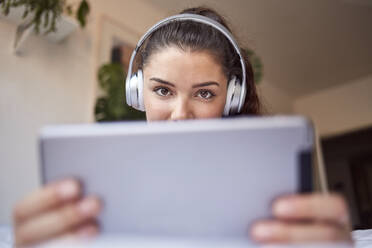 Portrait of young woman with digital tablet and headphones at home - JHAF00106