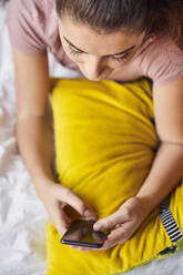 Young woman lying on bed using smartphone - JHAF00122