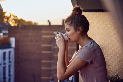 Junge Frau auf dem Balkon beim abendlichen Teetrinken, lizenzfreies Stockfoto
