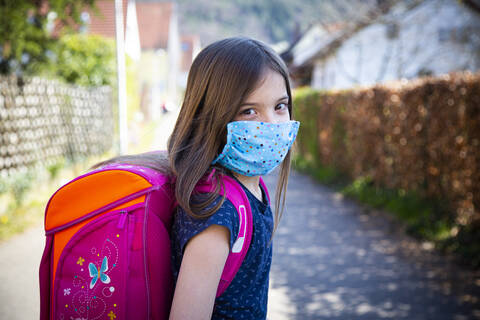 Girl with homemade protective mask on her way to school stock photo