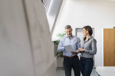 Businessman and businesswoman discussing paper in office - DIGF09676