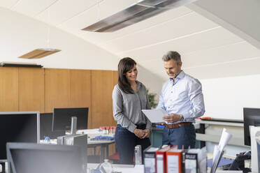 Geschäftsmann und Geschäftsfrau besprechen Papier im Büro - DIGF09677