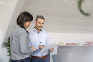 Businessman and businesswoman discussing paper in office - DIGF09680