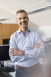 Portrait of smiling businessman in office - DIGF09683