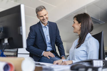 Businessman and businesswoman talking at desk in office - DIGF09691