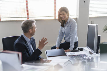 Businessman and businesswoman talking at desk in office - DIGF09693