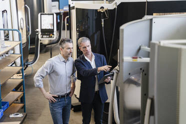 Businessmen in factory, having a meeting, using digital tablet - DIGF09724