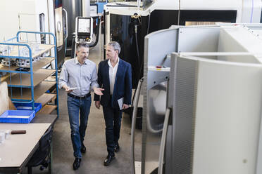 Businessmen in factory having a meeting in production hall - DIGF09728