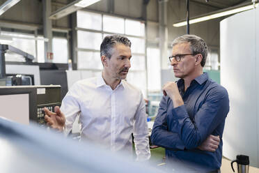 Businessmen in factory having a meeting in production hall - DIGF09752