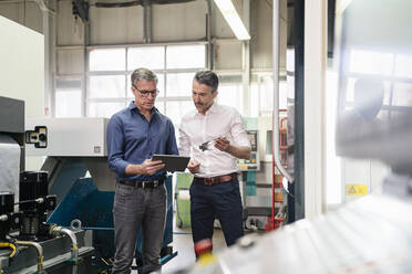 Businessmen in factory, having a meeting, using digital tablet - DIGF09760