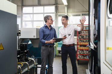 Businessmen in factory, having a meeting, using digital tablet - DIGF09761